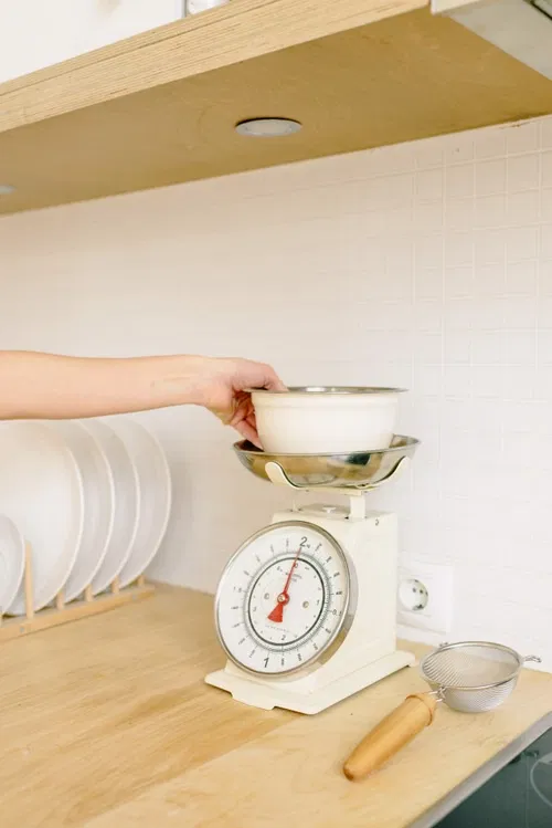 kitchen scale being used to weigh puppy food portions in grams for accurate UK puppy feeding schedule